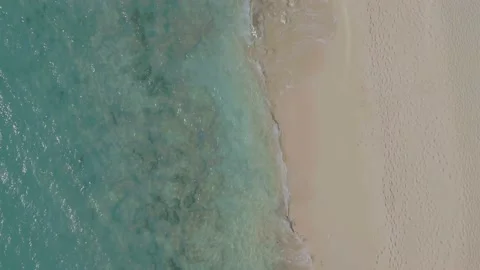 Aerial top down drone tracking shot of Caribbean sea lapping onto sandy beach Stock Footage 137497454