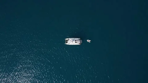 Aerial top down drone video of white catamaran anchored in dark blue waters Stock Footage 245311647