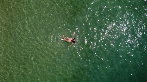 Aerial top down drone view of young woman swimming in clear sea waters Stock Footage 245544696