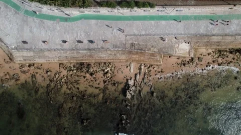 Aerial top down drone view of people enjoying a warm sunny day on the promenade Stock Footage 247981317