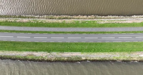 Aerial top down drone view on a asphalt road surrounded by water. Video stock 275091903