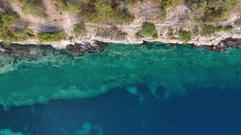 Aerial top down drone view of dirt pathway along a rocky sea shore in Greece Video stock 279582071