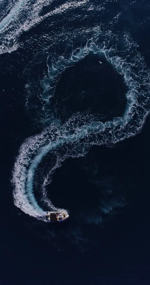 Aerial top down drone view of a speedboat forming an infinity loop on blue ocean Stock Footage 321228807