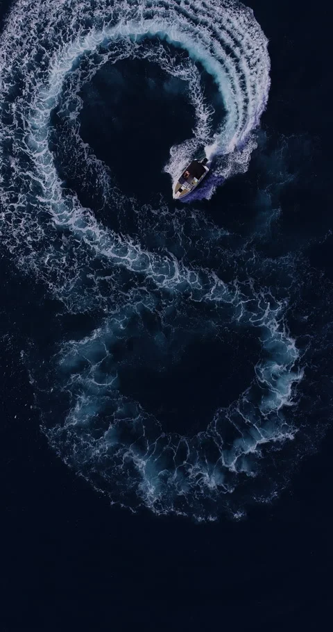 Aerial top down drone view of a speedboat forming an infinity loop on blue ocean Stock Footage 321232502