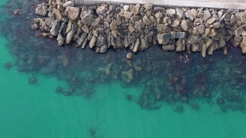 Aerial top-down drone view of rocky breakwater and turquoise water Stock Footage 322537465