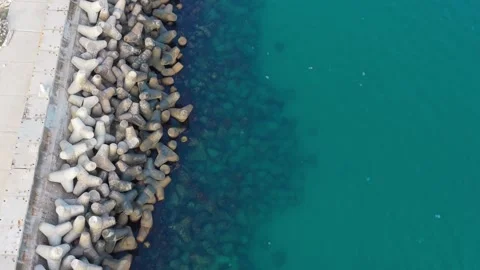 Aerial top-down drone view of breakwater blocks and turquoise water Stock Footage 322902054