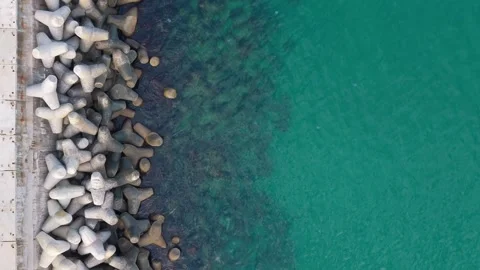 Aerial top-down drone view of breakwater blocks and turquoise water Stock Footage 322902060