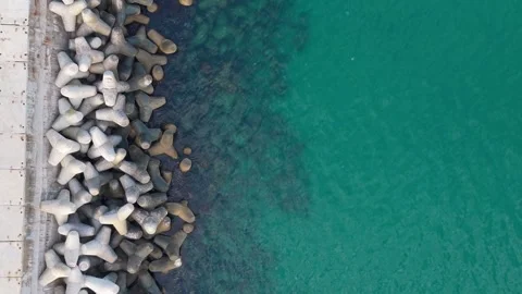Aerial top-down drone view of breakwater blocks and turquoise water Stock Footage 322902061