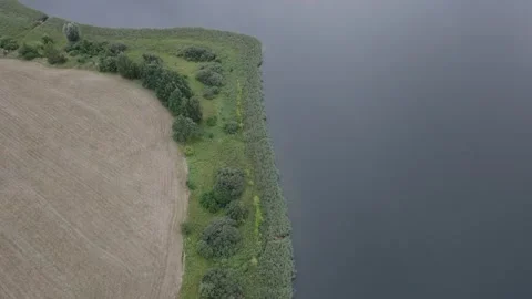 Aerial Top Down Flight Over Lake Shoreline and Fields Stock Footage 324977099