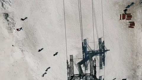 Aerial top down flyover shot of cable car pylons in winter with people nearby Stock Footage 169036975