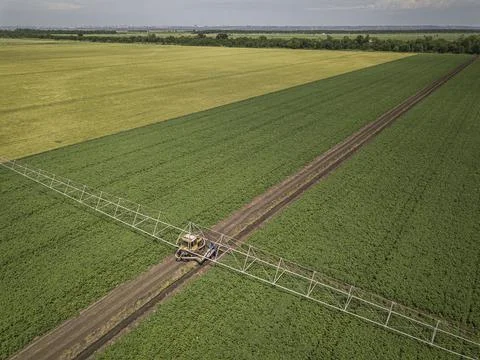 Aerial top down image of tractor spraying soil and young crop in springtime in Stock Photos