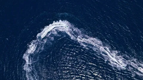 Aerial top-down of a jet ski making a circular pattern in clear ocean Stock Footage 287558008