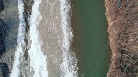 Aerial top down landscape of a river and the riverside with snow on a sunny day Video stock 152897682