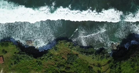 Aerial top down of massive waves of sea crashing against overgrown cliffs Stock Footage 201472823