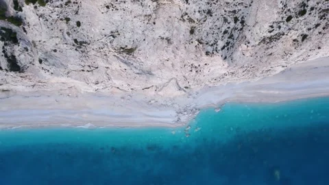 Aerial top down moving right to left view of wild small beach near a steep wall Video stock 245543505
