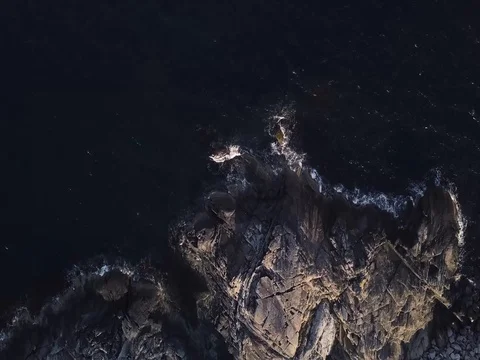 Aerial Top Down over Coast with Water Crashing against Rocks. Slow Spin Right Видео 82980922
