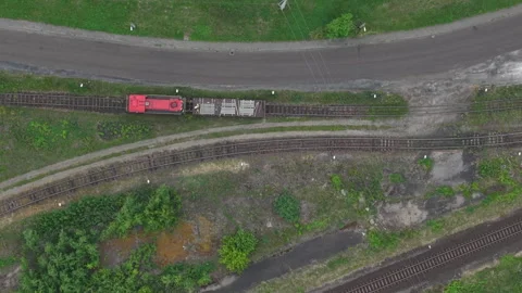 An aerial top down perspective shows a red industrial locomotive transporting Stock Footage 337091401