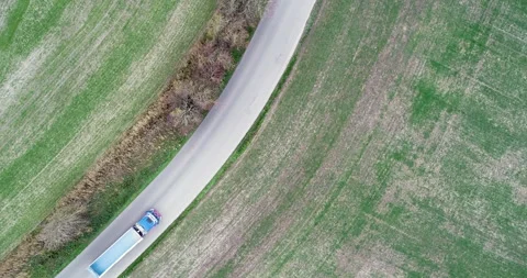 Aerial top down: Recycling garbage truck drives on road. Drone of green field 4K Stock Footage 139895016