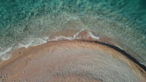 Aerial top down semicircular pebble beach with turquoise water Stock Footage 327013759