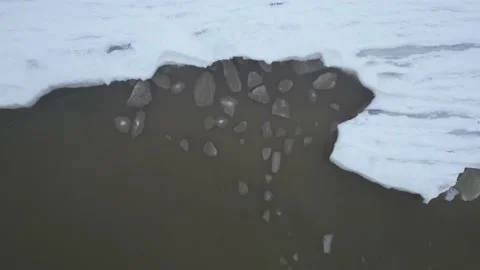 Aerial top down shot of broken off ice pieces washing against frozen sea Stock Footage 229545900