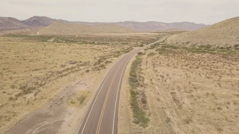 Aerial top down shot of empty two lane road in desert with scenic mountain view Vídeo Stock 118970803
