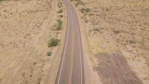 Aerial top down shot of empty two lane road in desert with scenic mountain view Stock Footage 118971075