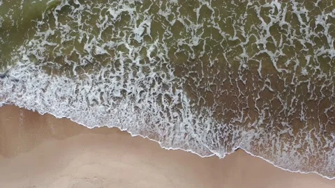 Aerial top down shot flying along shoreline. Waves crashing against beach Stock Footage 157691611
