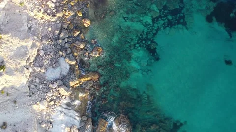 Aerial top down shot flying over waves crashing against rocks Stock Footage 196940195