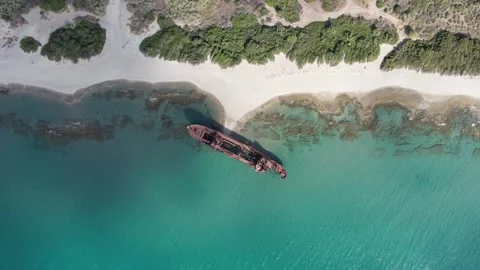 Aerial top down shot of rusty shipwreck beside tropical reef coastline Stock Footage 343944265