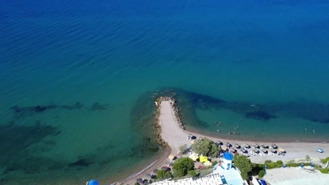 Aerial top down shot of a stone pier separating deep blue from beach. Stock Footage 343939521