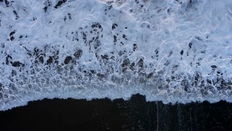 Aerial: Top down shot of Waves breaking on black sand beach Vidéo 223971152