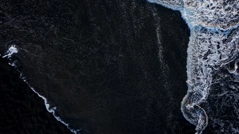Aerial: Top down shot of Waves breaking on black sand beach Vidéo 223973316