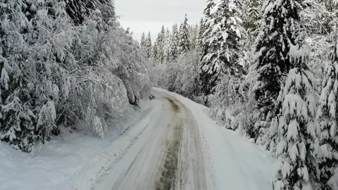 Aerial top down shot of white car drives along the road in winter snowy forest.  Video stock 221812974