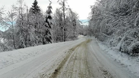 Aerial top down shot of white car drives along the road in winter snowy forest.  Video stock 221813751