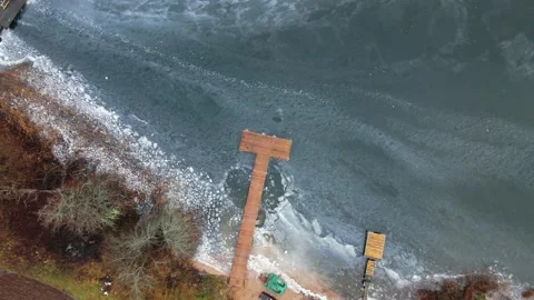 Aerial Top Down Sunrise View of lake pier zoom. Drone flies high over clouds. Stockbeeldmateriaal 169844459