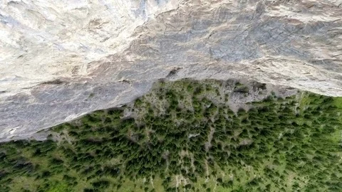 Aerial: top down tilting up while moving over edge of vertical mountain cliff Stock Footage 72422272