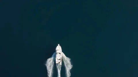 Aerial - Top down tracking shot of a bigger speed boat cruising on water Stock Footage