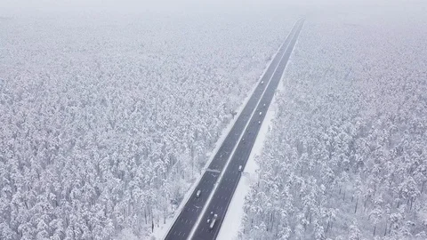 Aerial - Top down tracking shot of blue car drifting on snowy road in forest 動画素材 99836529