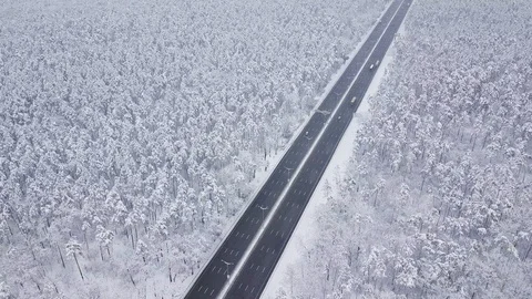 Aerial - Top down tracking shot of blue car drifting on snowy road in forest 動画素材 99836531