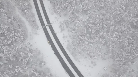 Aerial - Top down tracking shot of blue car drifting on snowy road in forest 動画素材 99836551