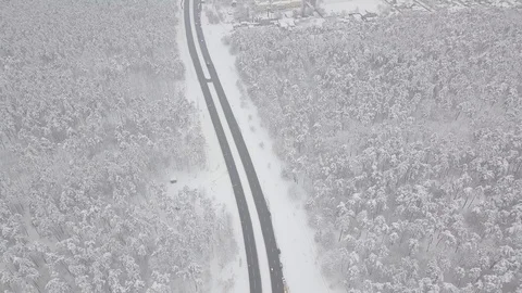 Aerial - Top down tracking shot of blue car drifting on snowy road in forest 動画素材 99836575
