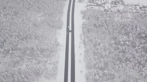 Aerial - Top down tracking shot of blue car drifting on snowy road in forest 動画素材 99836579