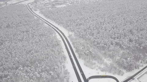 Aerial - Top down tracking shot of blue car drifting on snowy road in forest 動画素材 99836583