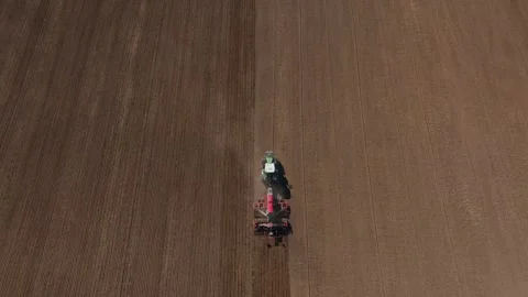 Aerial top down tractor pulls implement across vast tilled field Video stock 337583361