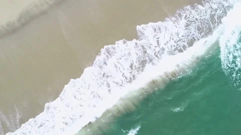 An aerial top down video of ocean waves crashing on a sandy beach relaxing .. Stock-Footage 314596690