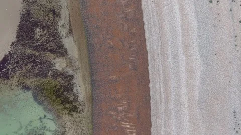 Aerial top-down view of abstract shoreline with sea, sand and wet stones Stock Footage 309765158