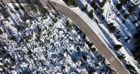Aerial top down view of Alpine road surrounded by snow and trees. Stock Footage 226066974