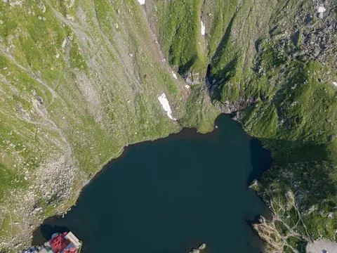 Aerial top-down view of alpine mountain lake with steep green slopes Stock Photos
