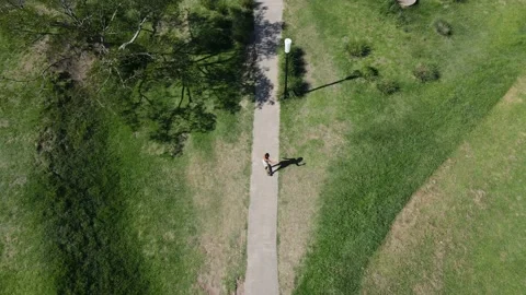 Aerial top down view of attractive girl skateboarding at park Stock Footage 153779745