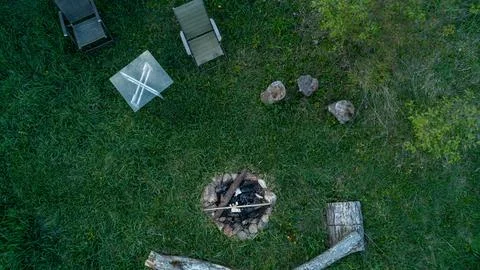 Aerial Top Down View of Backyard Fire Pit Ring and Lawn Chairs on Green Grass Stock Photos